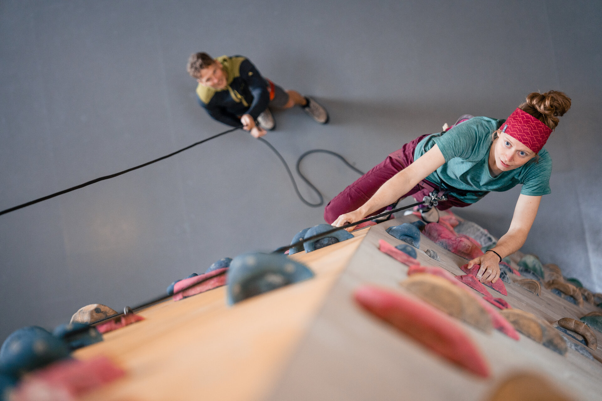 Eine Frau klettert in einer Kletterhalle, ihr Partner sichert sie. | © DAV/Marisa Koch